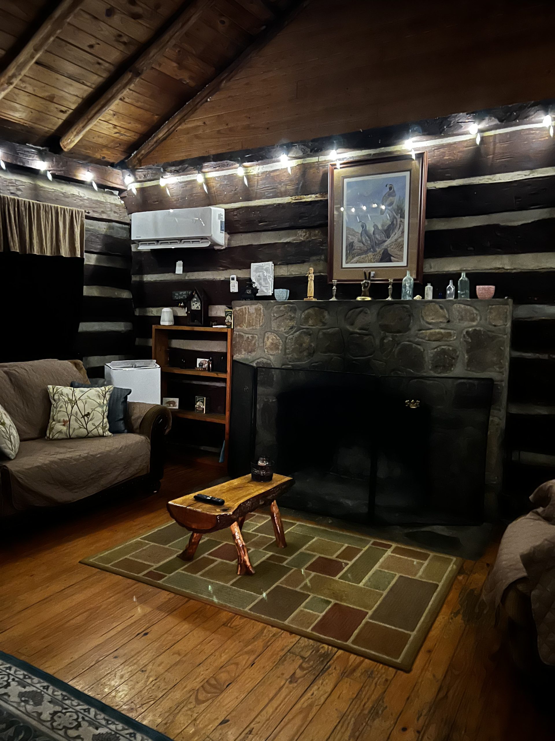 Cozy log cabin interior in the Smoky Mountains with a stone fireplace, warm lighting, and rustic wood beams